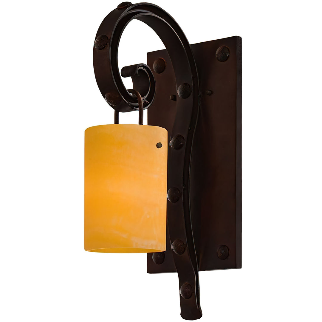 Antibes one-light wrought iron wall sconce with looping iron scroll, clavos-style studs, rectangular backplate and amber alabaster shade.