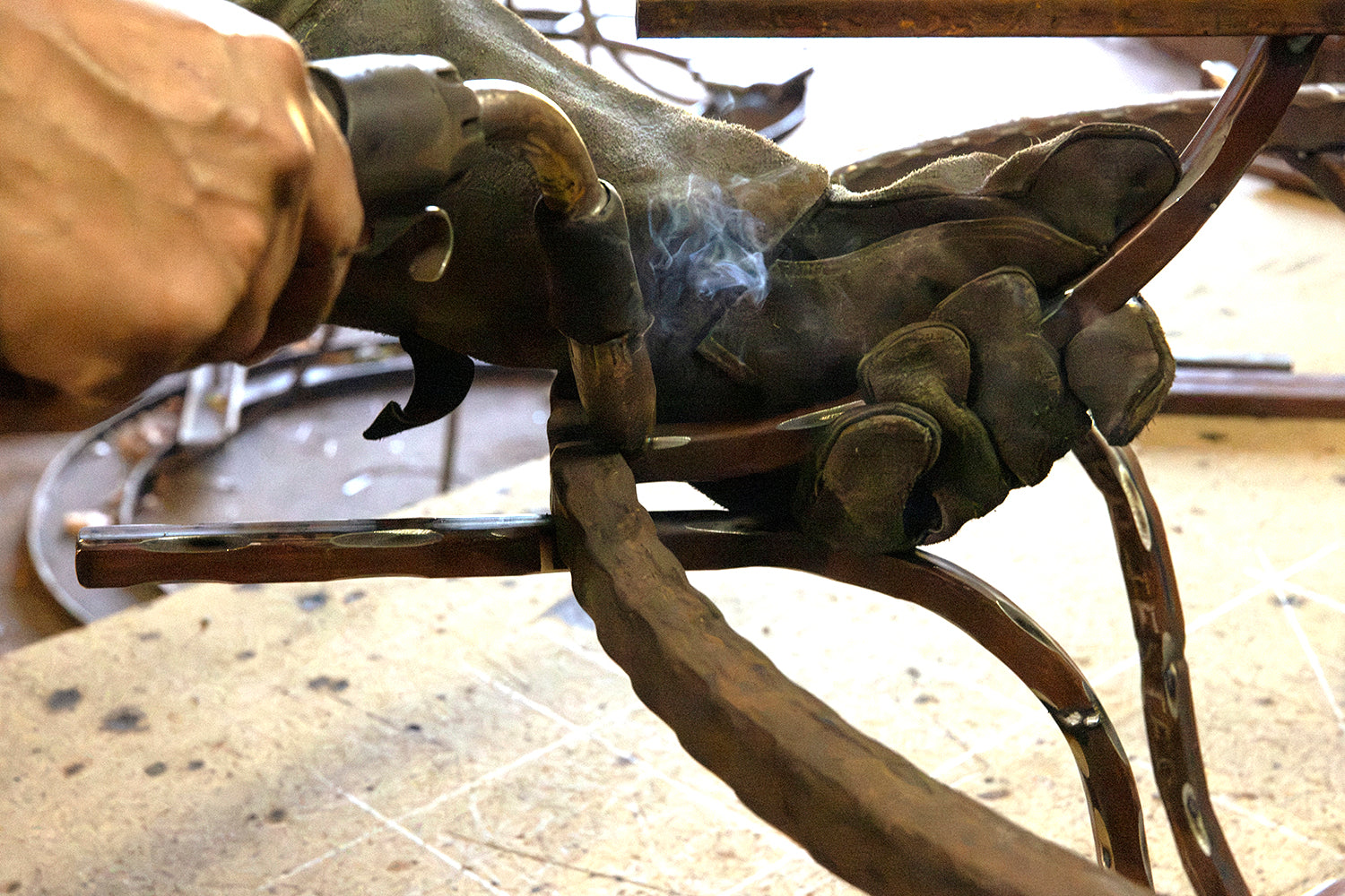 Ashore Lighting artisan heating and shaping curved ironwork by hand during lighting fixture fabrication in the workshop