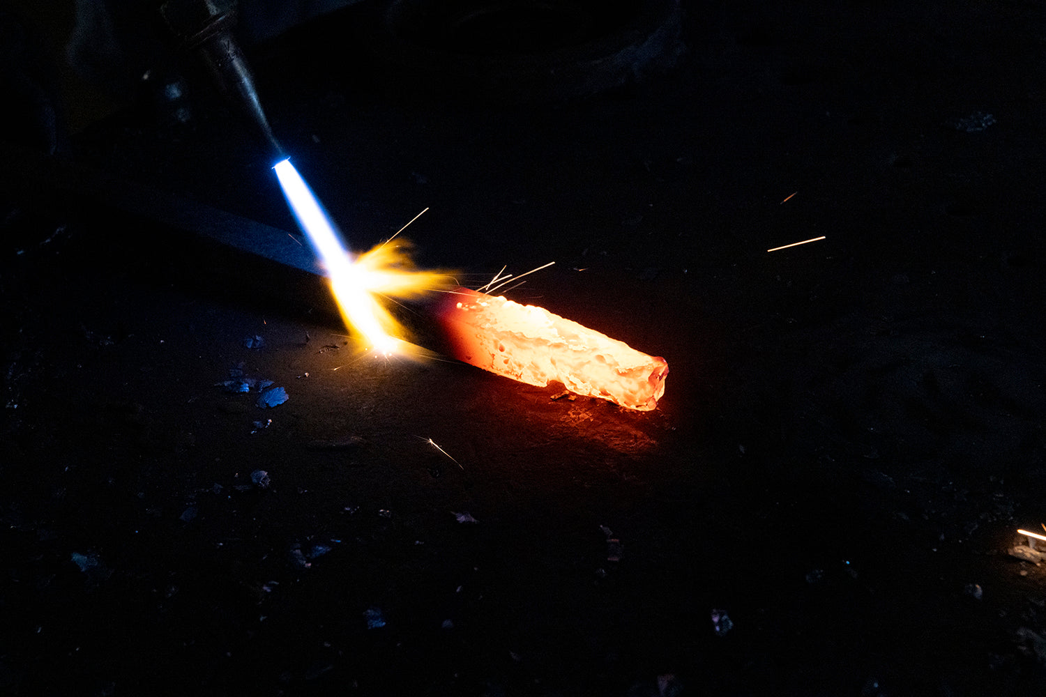 Ashore Lighting craftsman heating iron with a torch in the workshop before the metal is shaped for handcrafted lighting