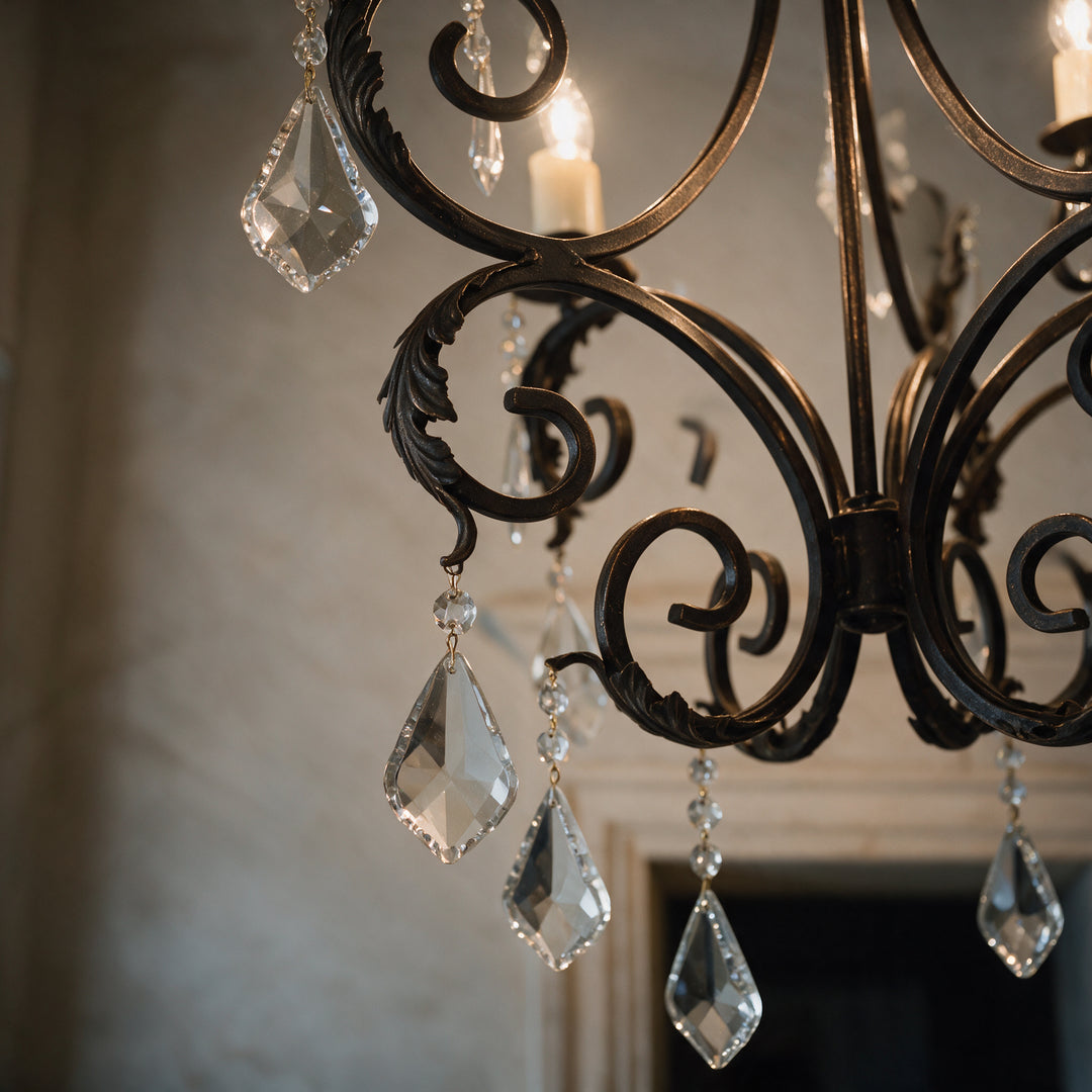 Close-up of Ashore Sculptural chandelier showing curved wrought iron scrollwork, leaf-like detailing, and hanging faceted crystal drops.