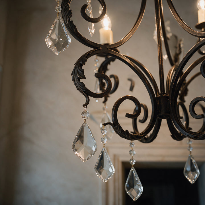 Close-up of Ashore Sculptural chandelier showing curved wrought iron scrollwork, leaf-like detailing, and hanging faceted crystal drops.
