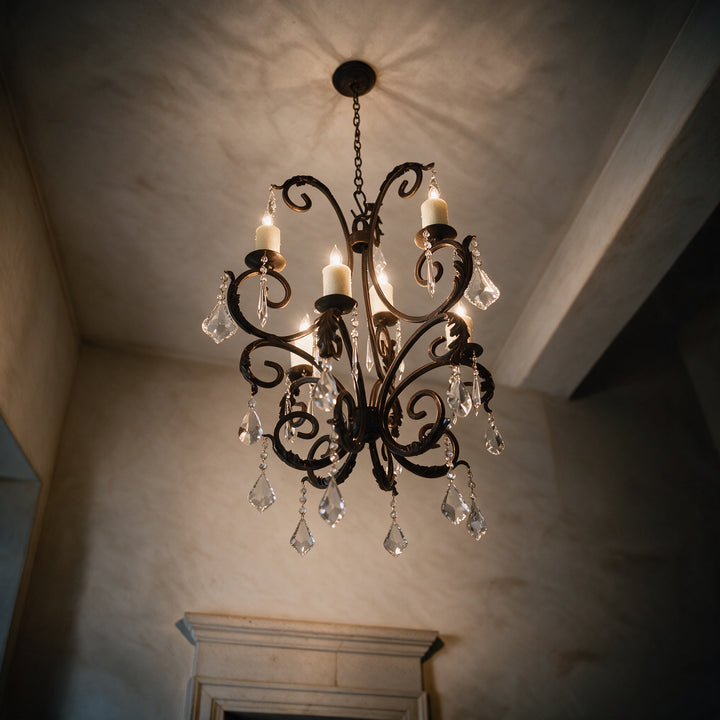 Low-angle view of the six-light Ashore Sculptural chandelier with candle-style lights, scrolling iron arms, and suspended clear crystals.
