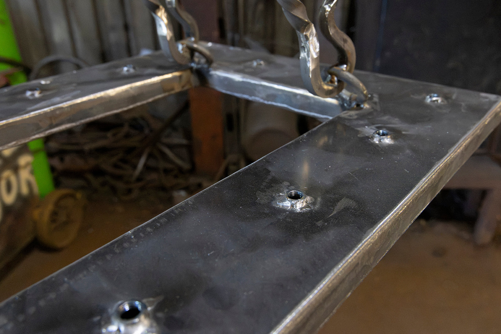 Close-up of rectangular wrought iron chandelier framework with welded mounting points and handcrafted suspension hardware in the Ashore Lighting workshop.