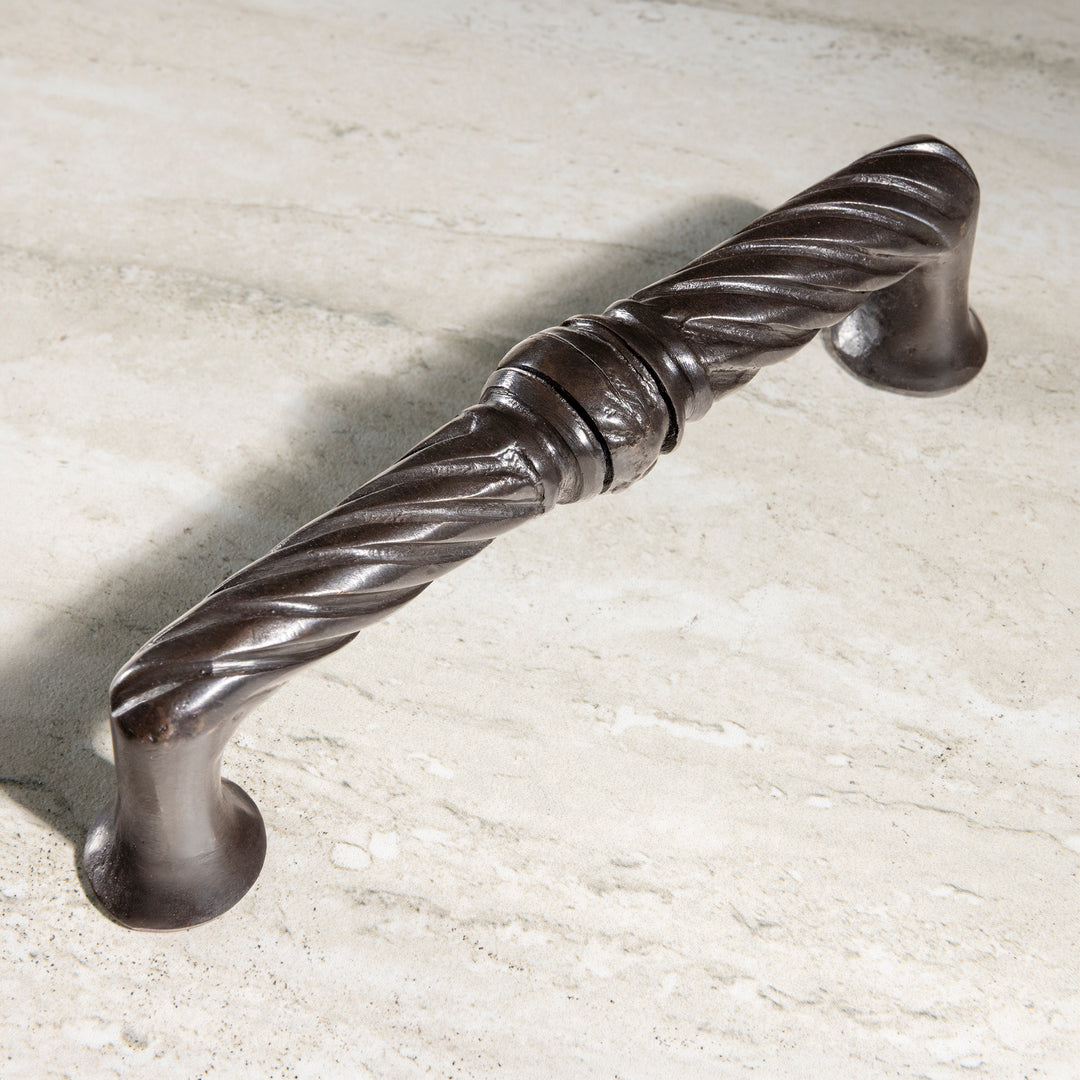 Cordoba bronze pull with handcast twisted spiral detailing shown in angled view on stone surface