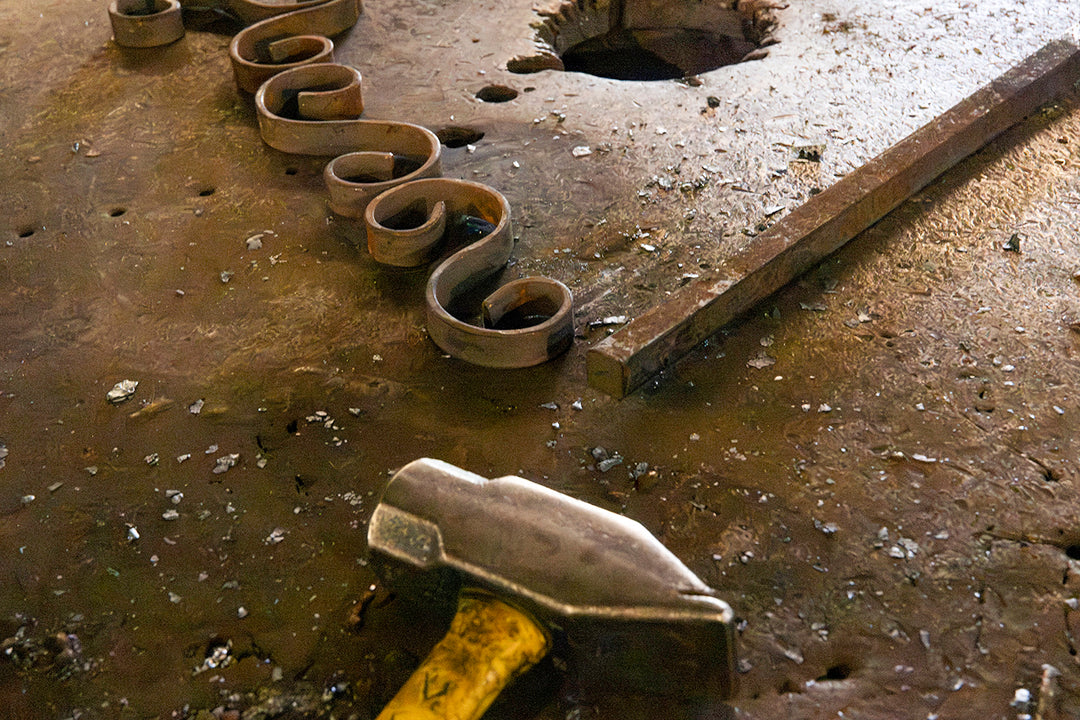Hand-shaped iron scrollwork arranged on a workbench during the fabrication of decorative components for an Ashore Lighting fixture.