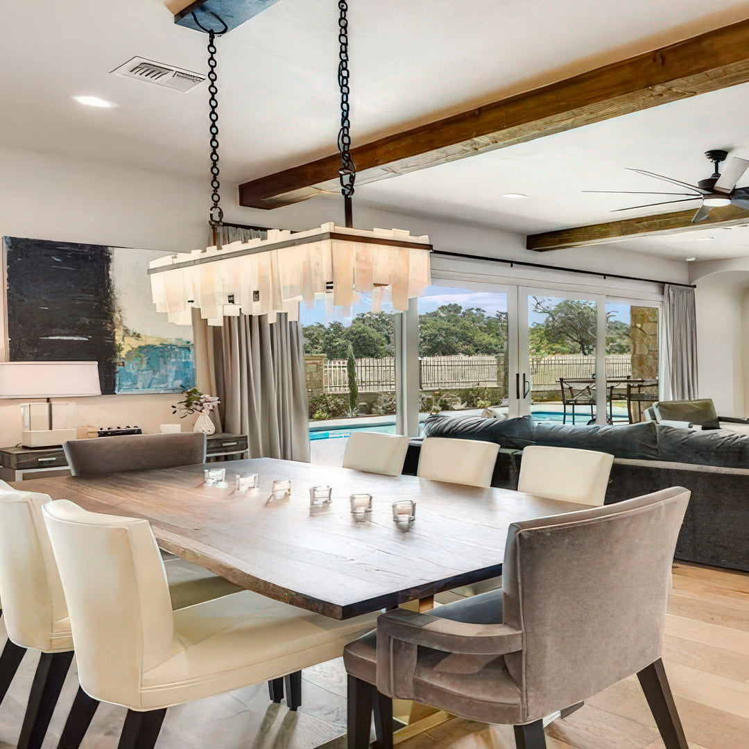 Harmony linear alabaster chandelier installed above a large dining table in a contemporary residential interior.