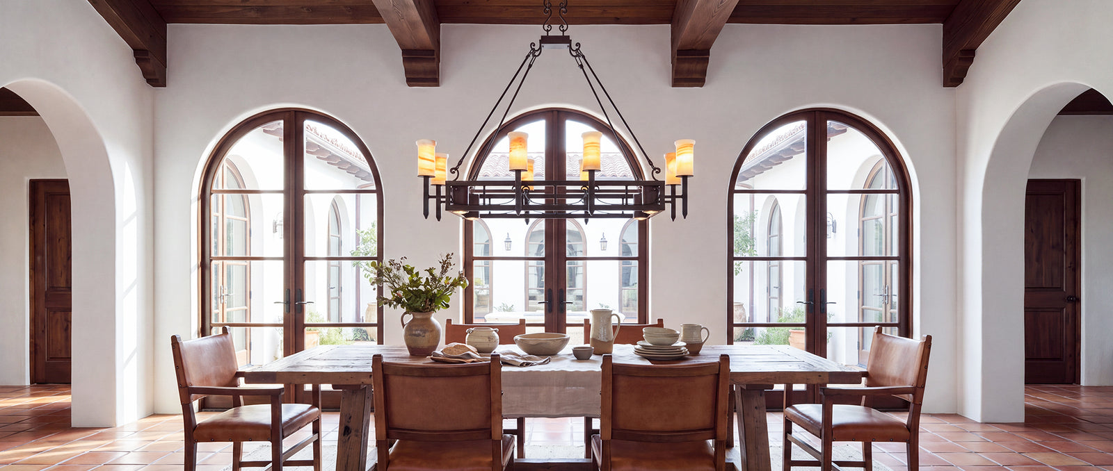 Mission Forge Spanish Colonial lighting collection represented by an architectural wrought iron chandelier with natural alabaster and forged detailing.
