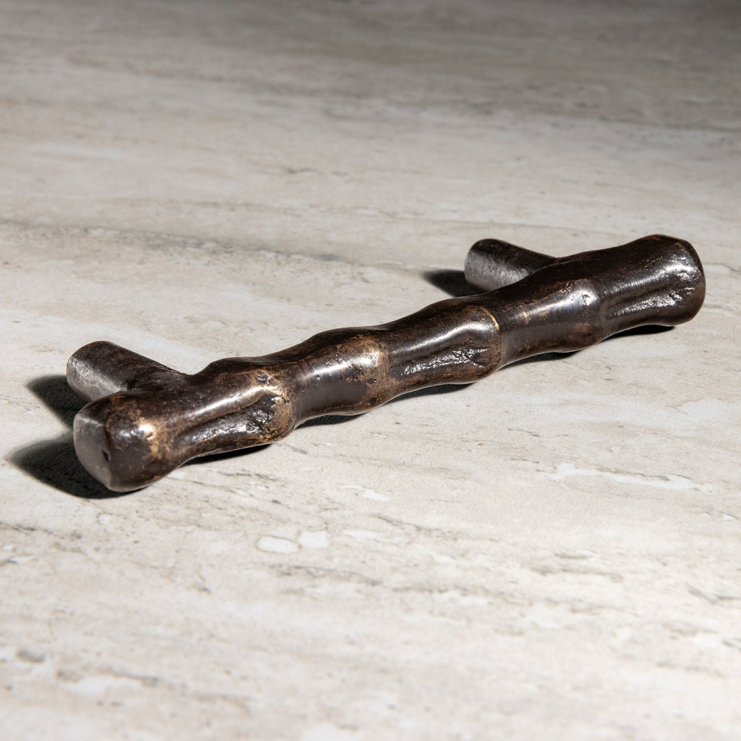 Osseo bronze pull with sculptural organic bone inspired form shown in angled view on stone surface