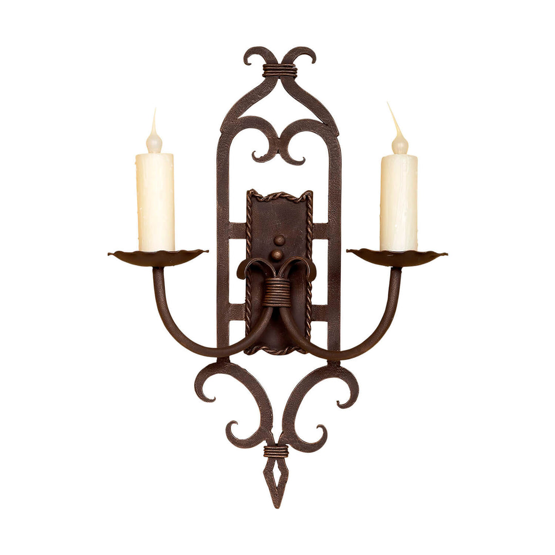 SC-816 two-light wrought iron wall sconce with symmetrical scrollwork frame, paired candle arms, central backplate, and pointed finial.