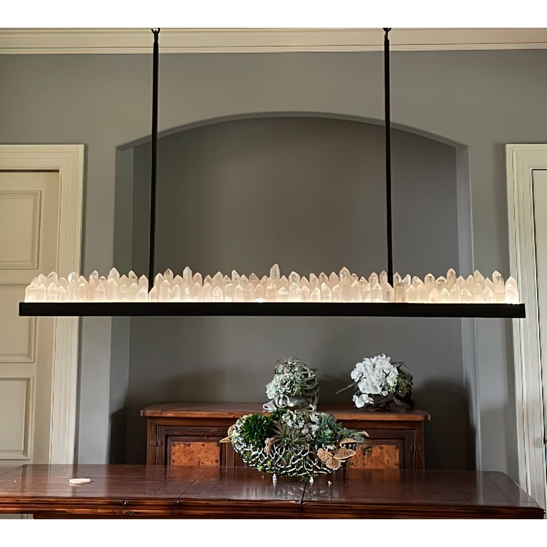 Skyline linear wrought iron quartz chandelier shown over a long table with a narrow iron frame and illuminated natural quartz crystal formations.